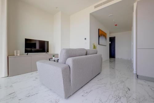a white living room with a couch and a tv at Mercury Tower Apartments in St Julian's