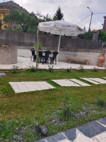 a table and chairs under an umbrella in a yard at Villa Aurea Rooms & More in Papasidero