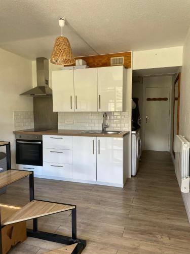 a kitchen with white cabinets and a table in it at Appartement au pied des pistes in Le Corbier