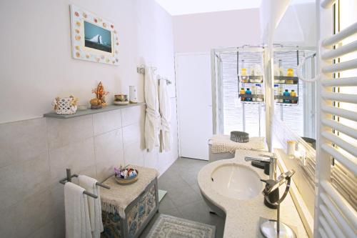 un bagno bianco con lavandino e specchio di Casa Lux ampio monolocale ad Alassio