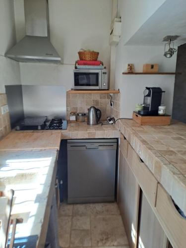 une cuisine avec une cuisinière et un micro-ondes dans l'établissement Maison de village - La Couronne, à Martigues