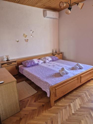 a bedroom with a large wooden bed with purple sheets at Apartmani Ino in Škrip