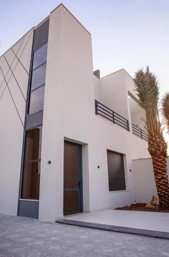 a white house with a palm tree in front of it at The Gray Villas in Sowayma