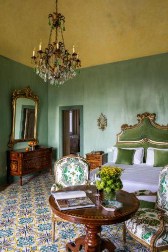 a bedroom with a bed and a table and a chandelier at Villa De Cillis Carafa in Torre del Greco