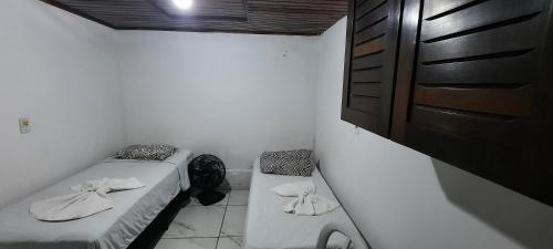 a small room with two beds and a cabinet at Pousada Don Ruan in Ponta Grossa