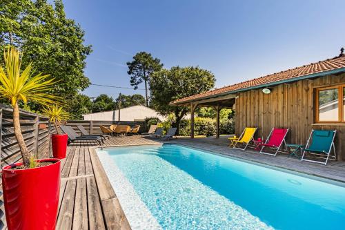 une piscine avec des chaises et une maison dans l'établissement villa bois typique du bassin avec piscine chauffée au bord du lac, La Gde Escoure, à Lacanau