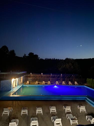 a group of chairs and a swimming pool at night at Pensiunea Hyperion Cormaia in Sîngeorz-Băi