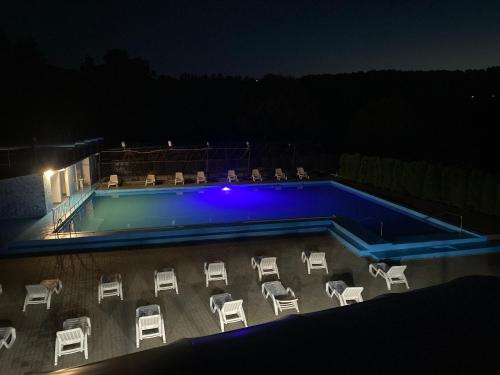 a swimming pool at night with chairs around it at Pensiunea Hyperion Cormaia in Sîngeorz-Băi