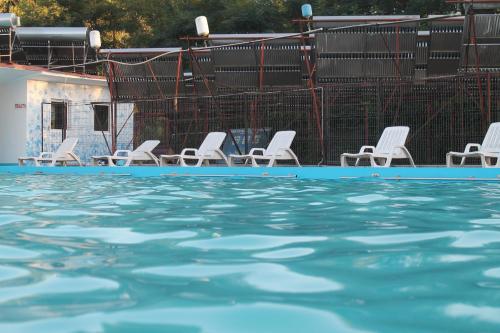a group of chairs sitting next to a swimming pool at Pensiunea Hyperion Cormaia in Sîngeorz-Băi