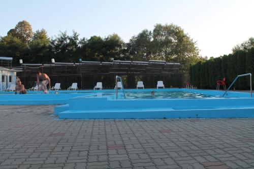 a large blue swimming pool with people in it at Pensiunea Hyperion Cormaia in Sîngeorz-Băi