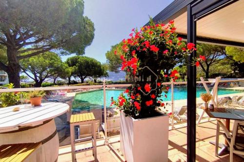 une terrasse avec des fleurs rouges et une piscine dans l'établissement La Napoule plage et vue mer, à Mandelieu-la-Napoule