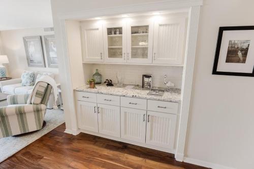 a kitchen with white cabinets and a living room at Paradise Found Beachfront Litchfield By the Sea in Pawleys Island