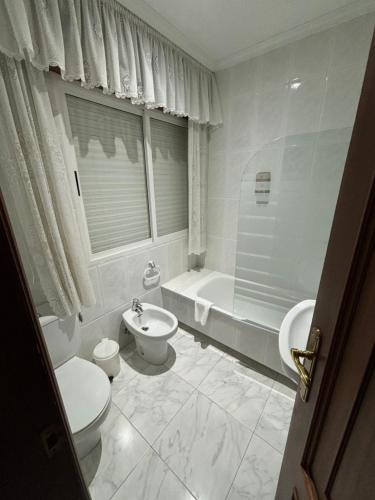 a bathroom with two toilets and a tub and a sink at Hotel Xacobeo in Outeiro