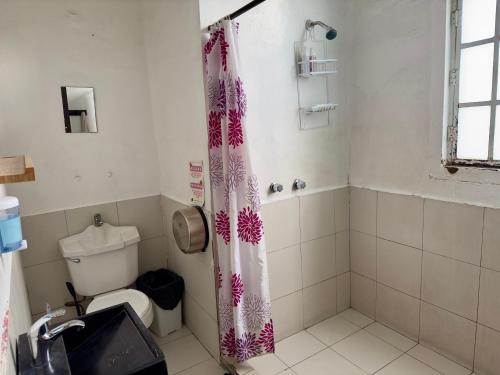 a bathroom with a toilet and a shower curtain at Massiosare El Hostal in Mexico City