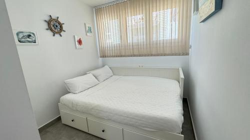 a small bedroom with a bed with a window at Apartamento con parking en Torre Almenara in Punta Umbría
