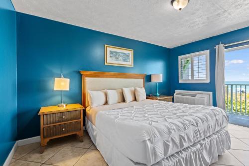 a bedroom with a bed and a blue wall at Ocean View Hotel Room with Balcony- King Bed #19 in Fort Pierce