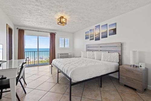 a bedroom with a bed and a table and a desk at Ocean View Hotel Room with Balcony- King Bed #25 in Fort Pierce
