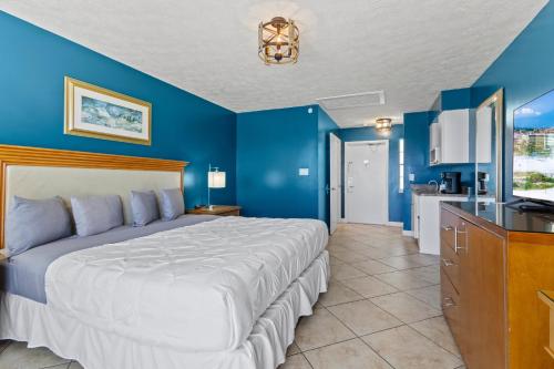 a bedroom with a large bed and a blue wall at Ocean View Hotel Room with Balcony- King Bed #21 in Fort Pierce