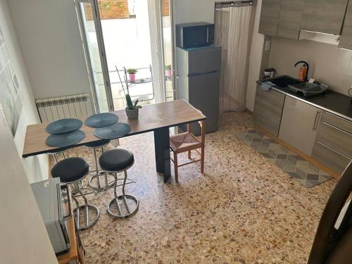 une cuisine avec une table et des tabourets dans une pièce dans l'établissement Appart Yucca, à Lézignan-Corbières