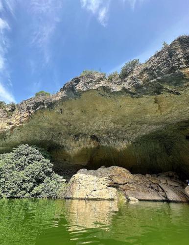 a cave in the side of a mountain with green water at VUT EL Mogollón in Guadalajara