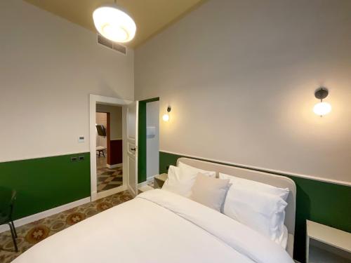 a bedroom with a white bed and a green wall at Maison Ines Luxury B&B in Messina