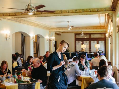 a woman standing in a dining room with people at The Plaza Hotel - Milwaukee in Milwaukee
