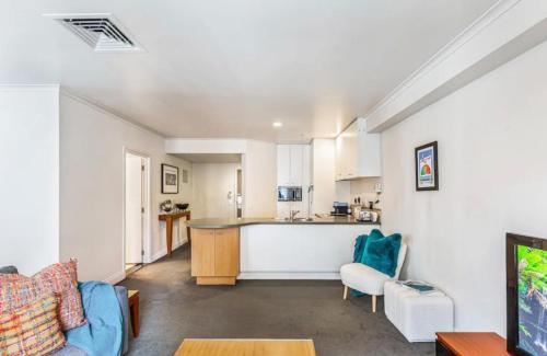 a living room with a couch and a kitchen at City Serenity 1 BR Apt with Pool - Gym in Auckland