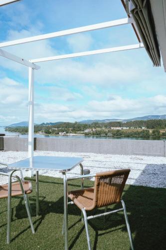 a table and chairs on a patio with a view of the water at Férias em Cerveira in Vila Nova de Cerveira