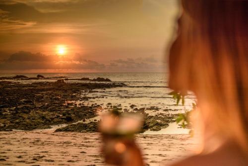 a woman standing on the beach looking at the sunset at Cala Luna Boutique Hotel & Villas in Tamarindo