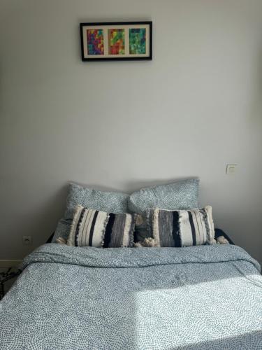 un lit avec des oreillers et un tableau sur le mur dans l'établissement Studio Gabriel, à Villeurbanne