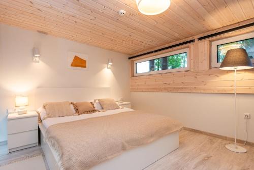 ein Schlafzimmer mit einem Bett und zwei Fenstern in der Unterkunft Pajūrio namelis FAMILY BEACH HOUSE su baseinu in Palanga