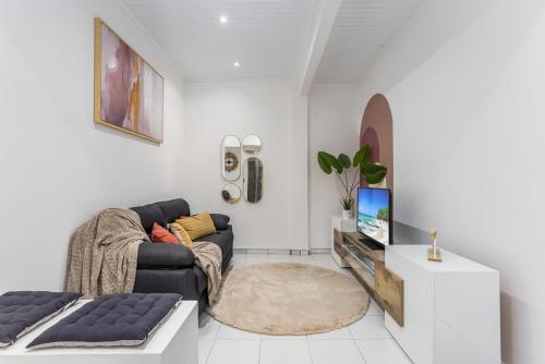 a living room with a couch and a tv at Foyal Toloman - Emeraude Lodge in Saint-Joseph
