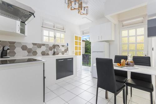 a white kitchen with a table and chairs at Foyal Toloman - Emeraude Lodge in Saint-Joseph