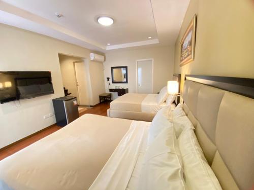 a hotel room with two beds and a flat screen tv at Prism Hotel in Angeles