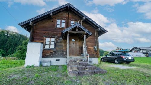 a wooden house with a car parked in front of it at Vacation House Kawaraya in Senboku