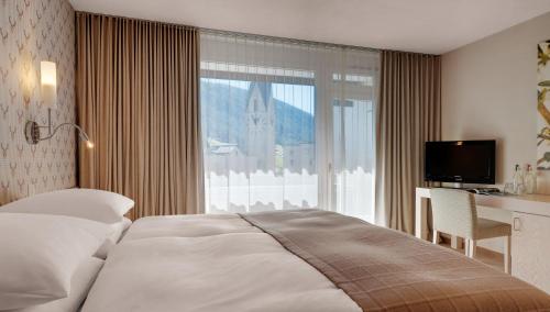 a bedroom with a bed and a desk and a window at Morosani Posthotel in Davos