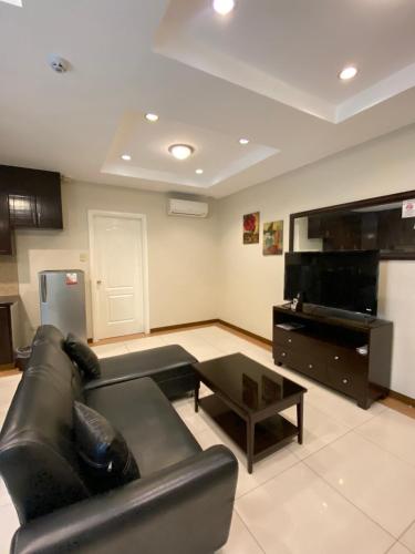 a living room with a black leather couch and a piano at Prism Hotel in Angeles