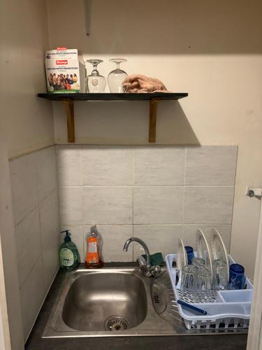 - un évier de cuisine avec de la vaisselle sur une étagère au-dessus dans l'établissement Chambre 2 personnes, à Saint-Vallier