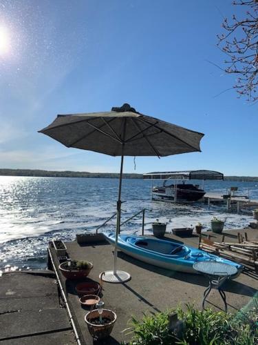 a beach with an umbrella and a boat on the water at Water's Edge on Canandaigua Lake 2 bedroom only October 15-April 30 El Borde del Agua de Canandaigua in Canandaigua