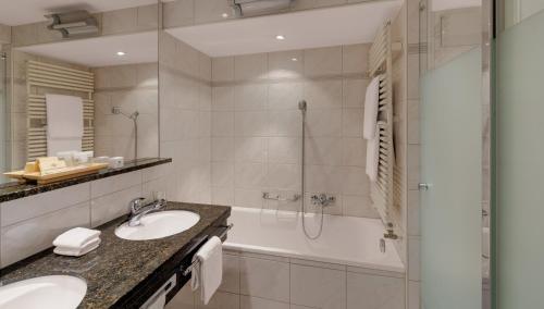 a bathroom with a tub and a sink and a shower at Morosani Posthotel in Davos