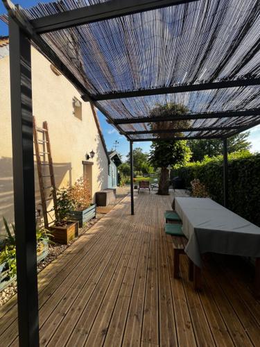 une terrasse en bois avec une pergola et une table dans l'établissement Le Nid - Maison accueillante avec accès donnant sur le Cher, à Azay-sur-Cher