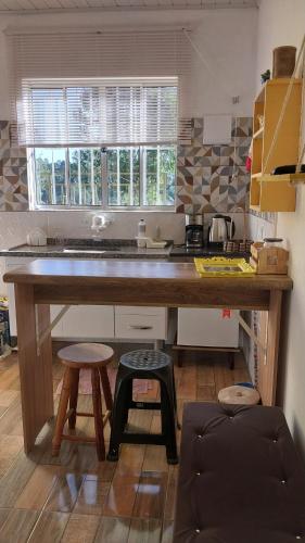 a kitchen with a large wooden counter with two stools at Kitnet na serra - Campos do Jordão in Campos do Jordão