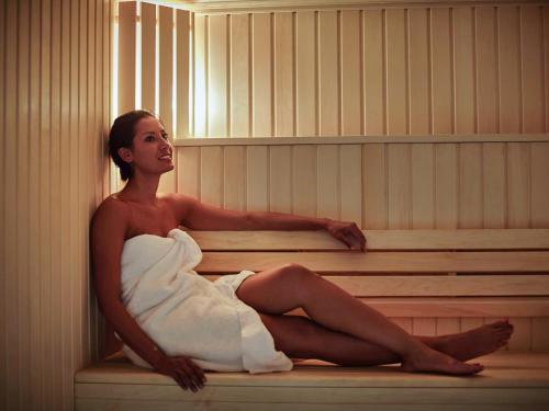 a woman is sitting in a bath tub at Pullman Paris Roissy Cdg Airport in Roissy-en-France