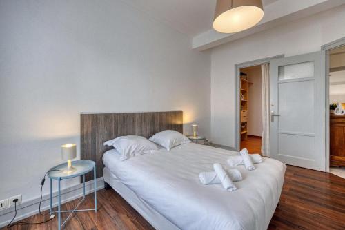 - une chambre avec un grand lit blanc et des oreillers blancs dans l'établissement Le Berriat - Gare - Palais de Justice, à Grenoble