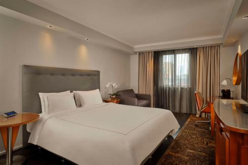 a hotel room with a large white bed and a desk at Park Plaza Victoria London in London