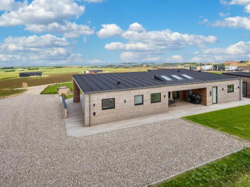 a house with a black roof on a gravel driveway at 5 star holiday home in Lemvig-By Traum in Lemvig