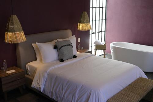 a bedroom with a white bed and a bath tub at Casa Martina Guest House in Pátzcuaro