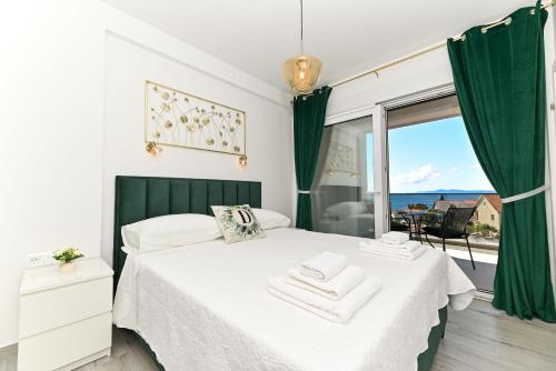 a bedroom with a white bed with a window at Apartments Diva in Trogir