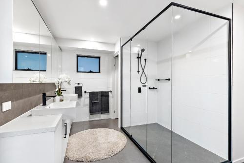 a white bathroom with a shower and a sink at Hedge Apartments by CLLIX in Buddina