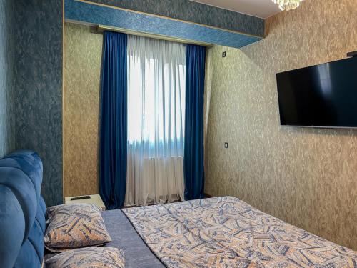 a bedroom with a bed and a flat screen tv at Downtown Residence in Tbilisi City